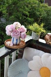 Photo of Beautiful pink peony flowers in vase and potted plant on balcony railing outdoors