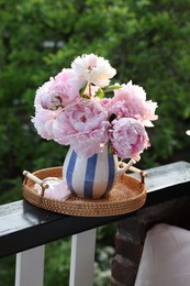 Beautiful pink peony flowers in vase on balcony railing outdoors