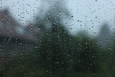 View on buildings through window with water droplets on rainy day, closeup