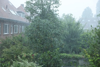 Photo of View of buildings and trees under pouring rain