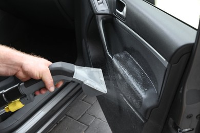 Photo of Man cleaning car door with vacuum cleaner, closeup