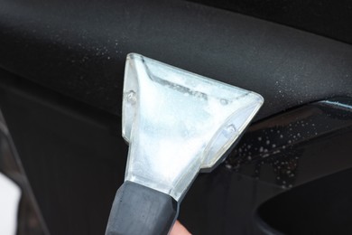 Photo of Cleaning car interior with vacuum cleaner, closeup