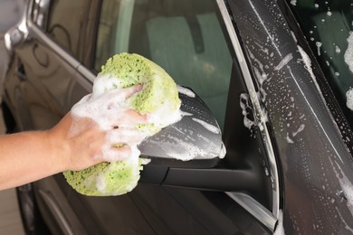 Photo of Man washing auto with sponge at car wash, closeup