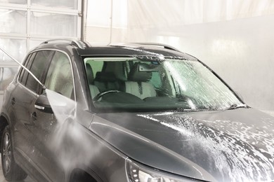 Photo of Washing auto with high pressure water jet at car wash, closeup