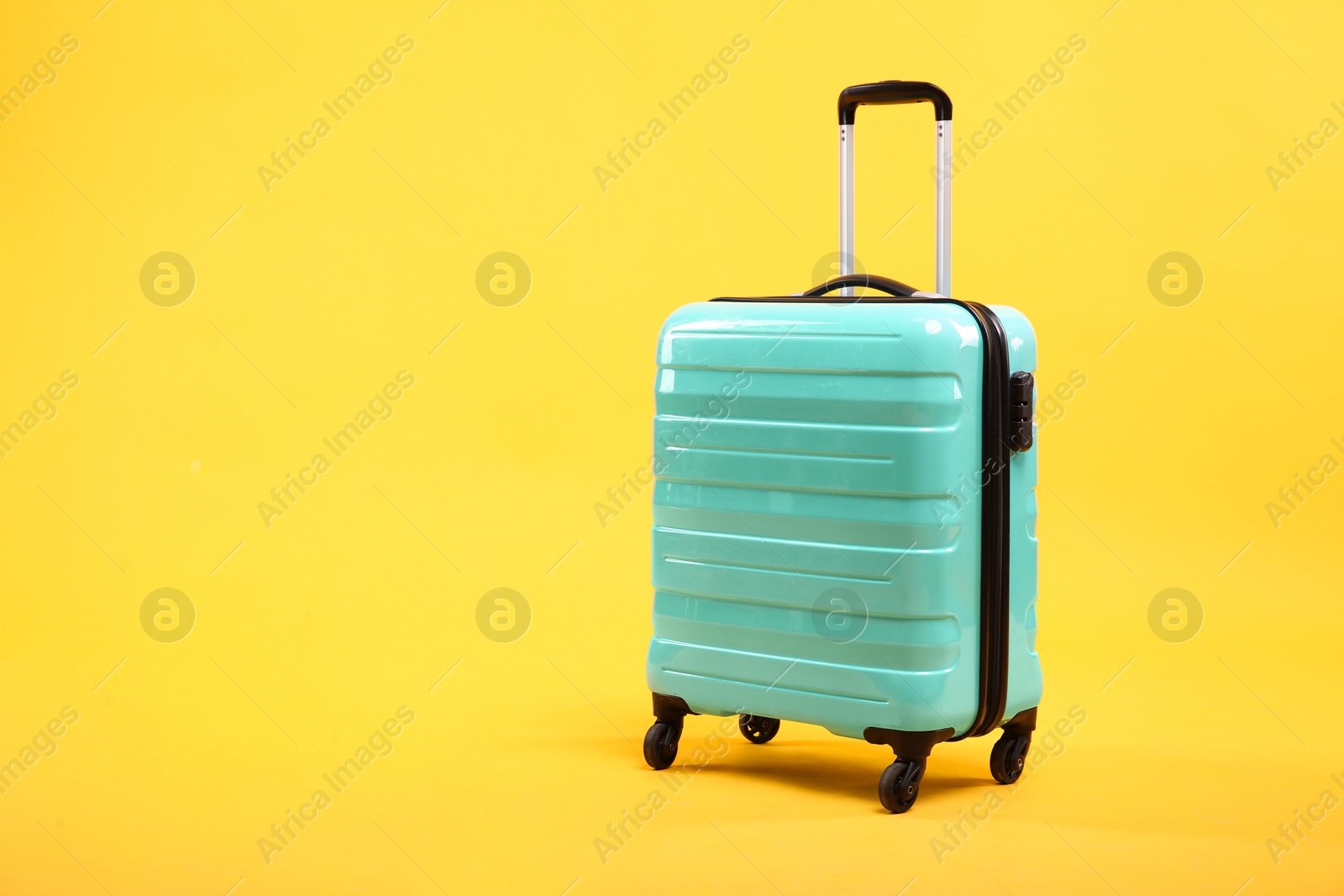 Photo of One new turquoise suitcase on yellow background, space for text