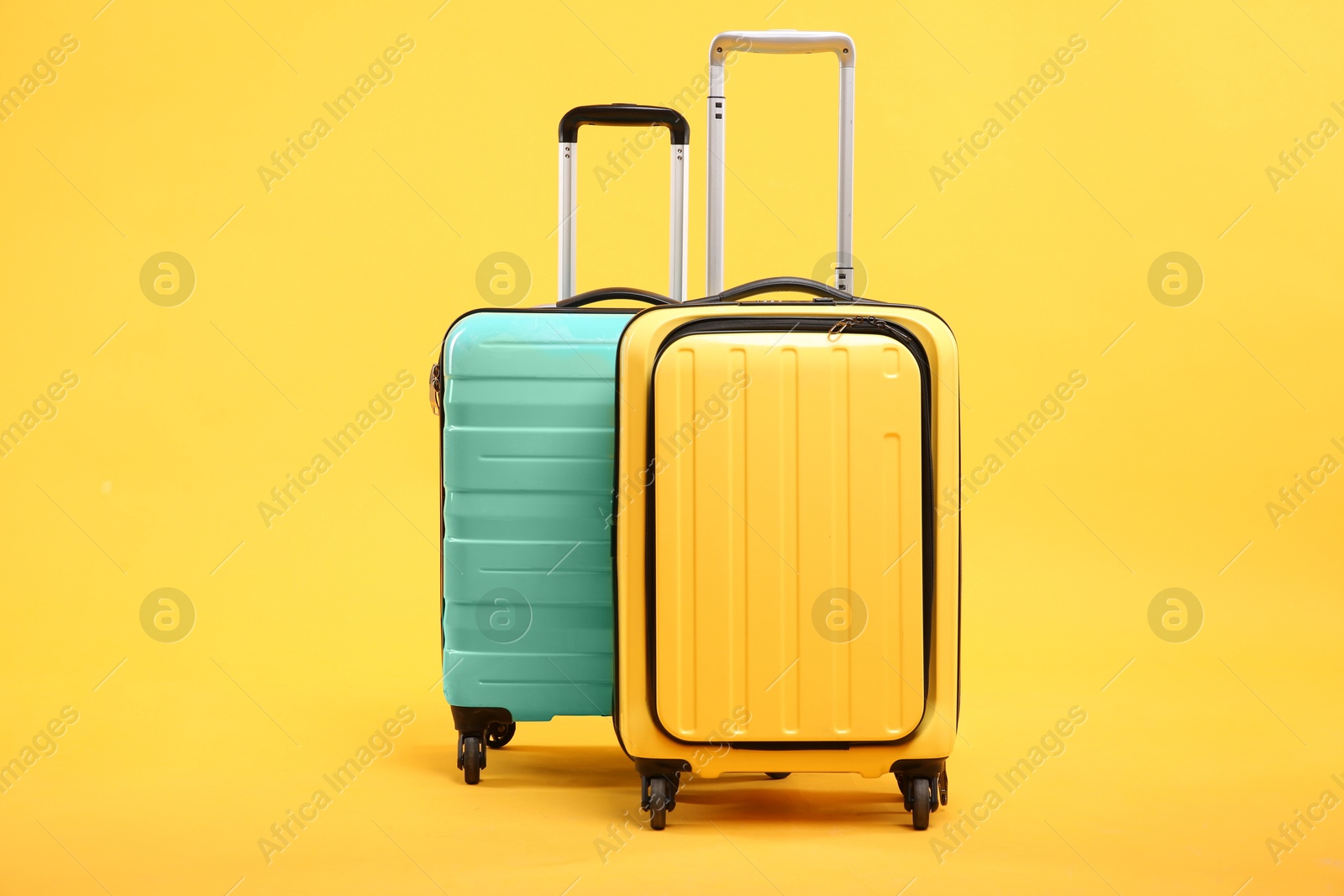 Photo of Two different bright suitcases on yellow background