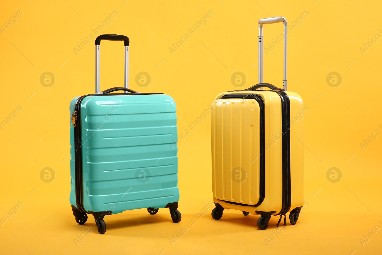 Photo of Two different bright suitcases on yellow background