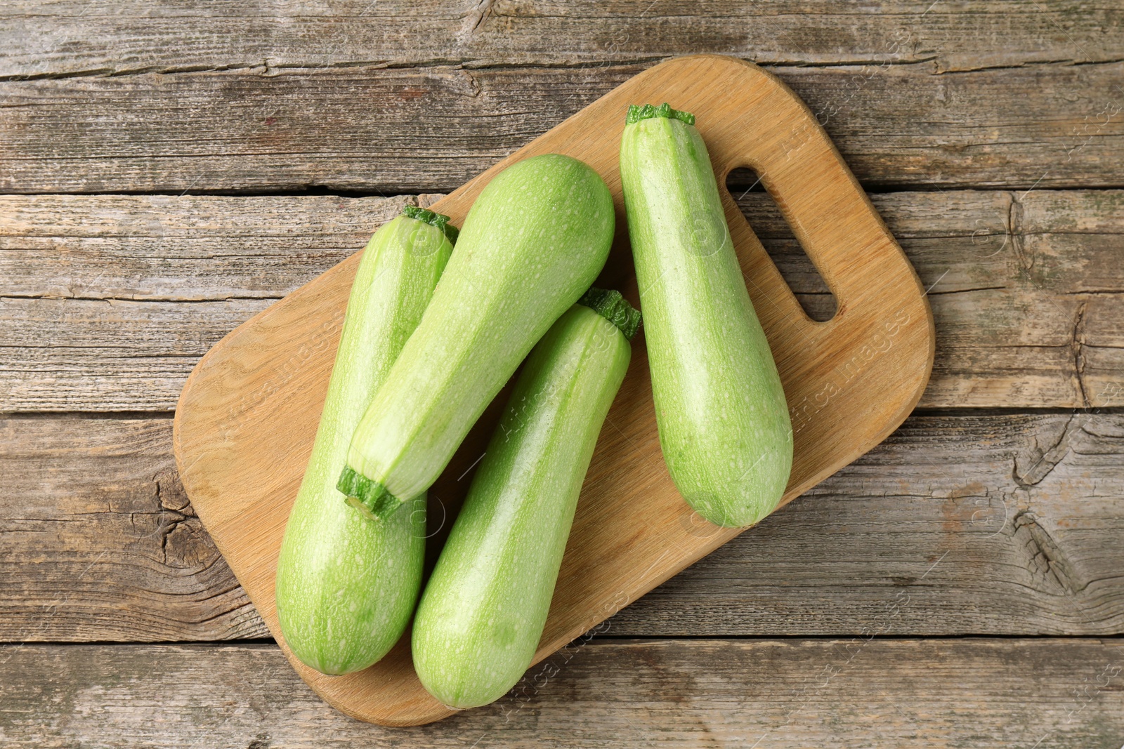 Photo of Board with fresh zucchinis on wooden table, top view