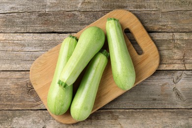 Photo of Board with fresh zucchinis on wooden table, top view