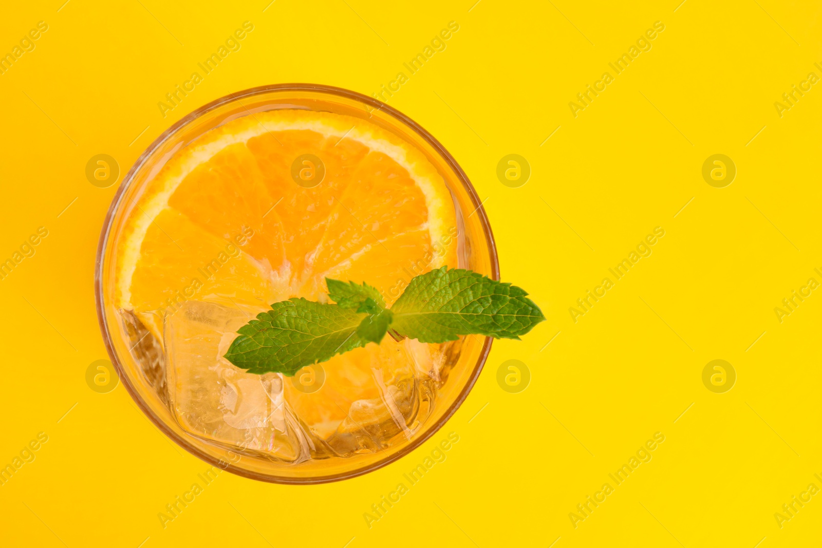 Photo of Refreshing water with orange and mint in glass on yellow background, top view. Space for text