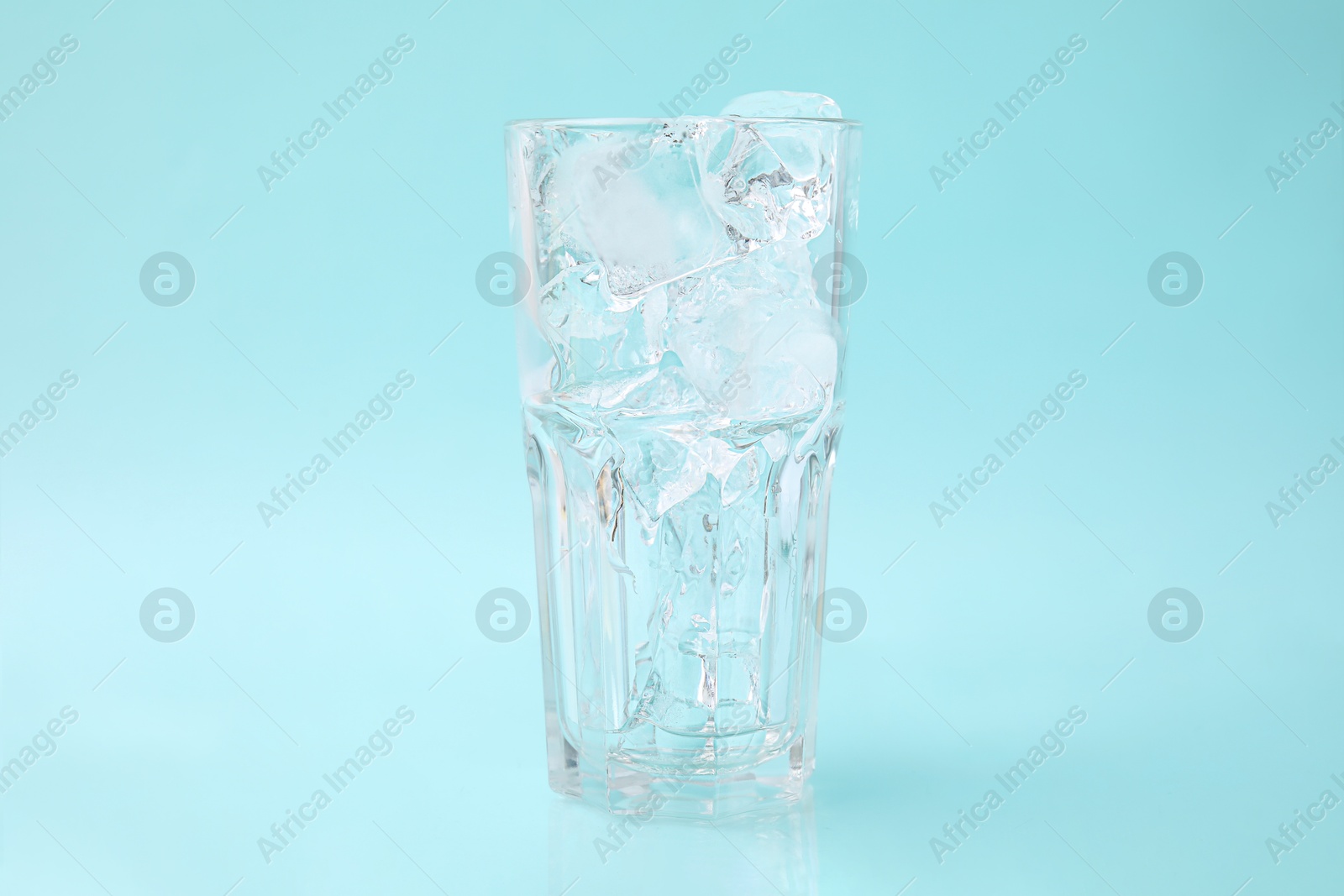 Photo of Refreshing water with ice cubes in glass on light blue background