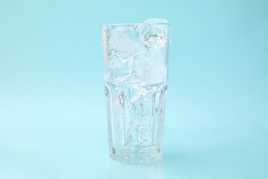 Photo of Refreshing water with ice cubes in glass on light blue background