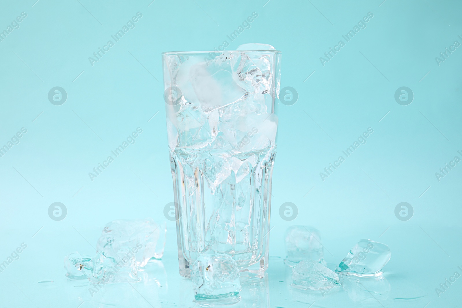 Photo of Refreshing water in glass with ice cubes on light blue background