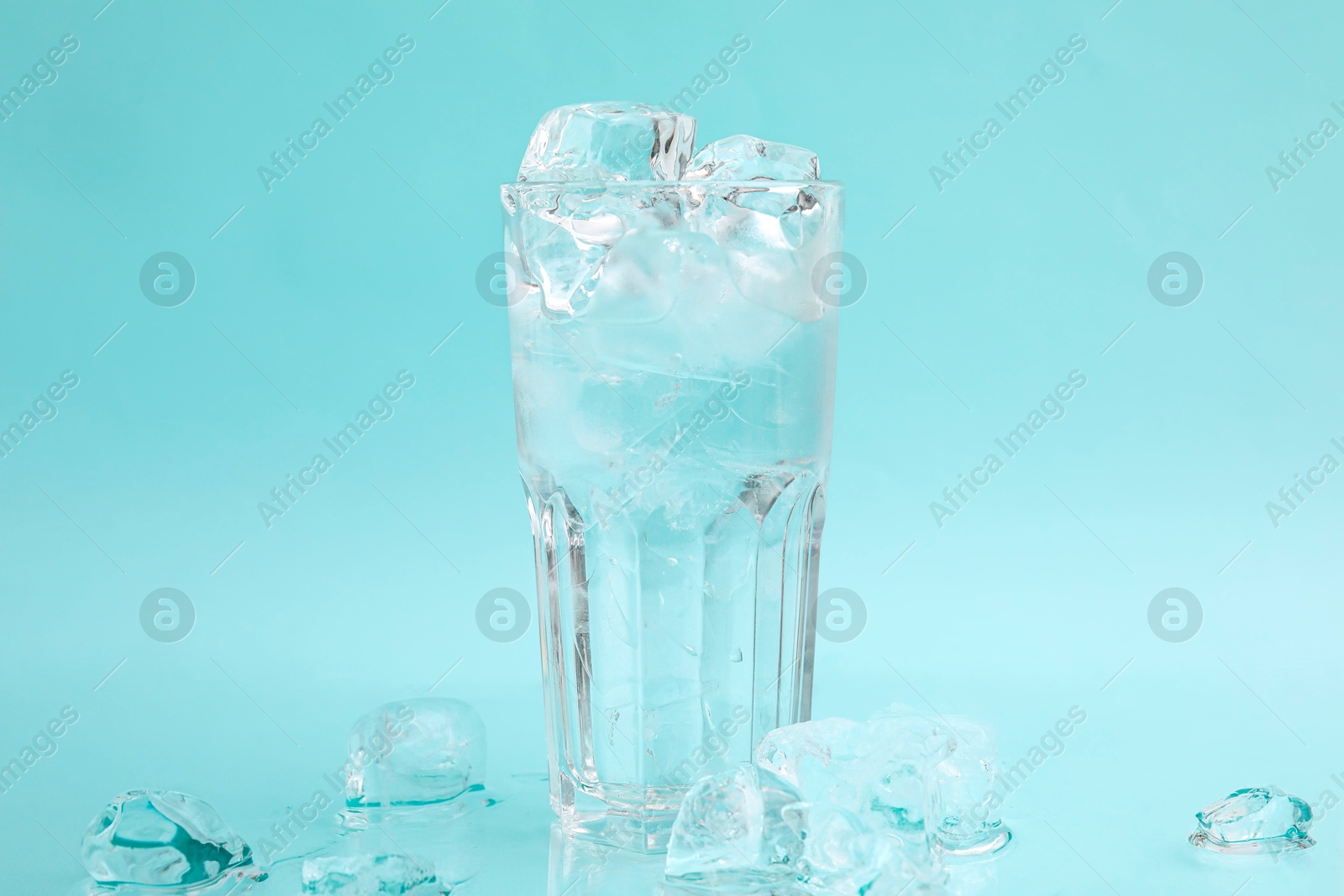 Photo of Refreshing water in glass with ice cubes on light blue background