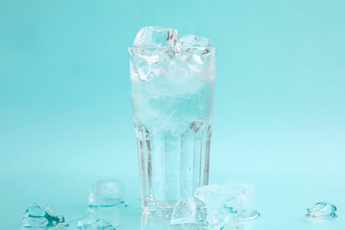 Photo of Refreshing water in glass with ice cubes on light blue background