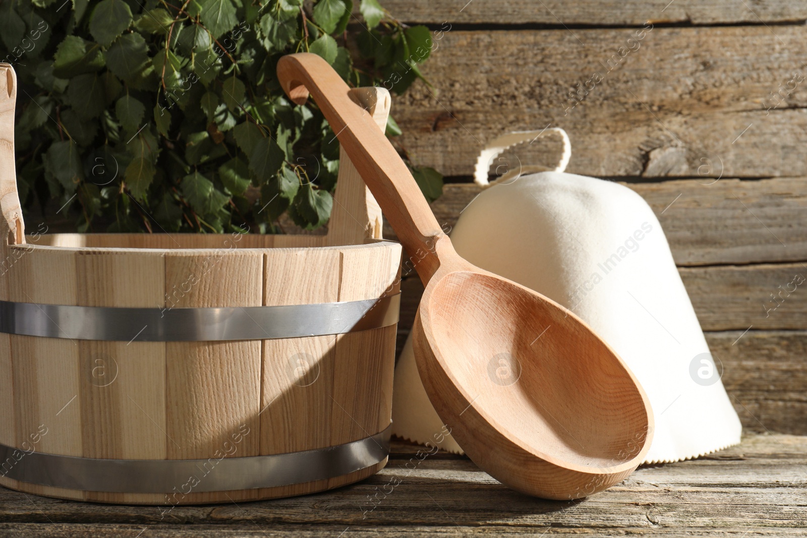 Photo of Sauna equipment. Bucket, felt wool hat and ladle on wooden surface