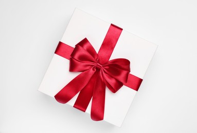 Photo of Gift box with red bow on light grey background, top view