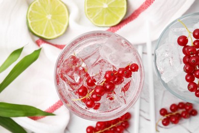 Refreshing water with red currants in glass on light table, flat lay