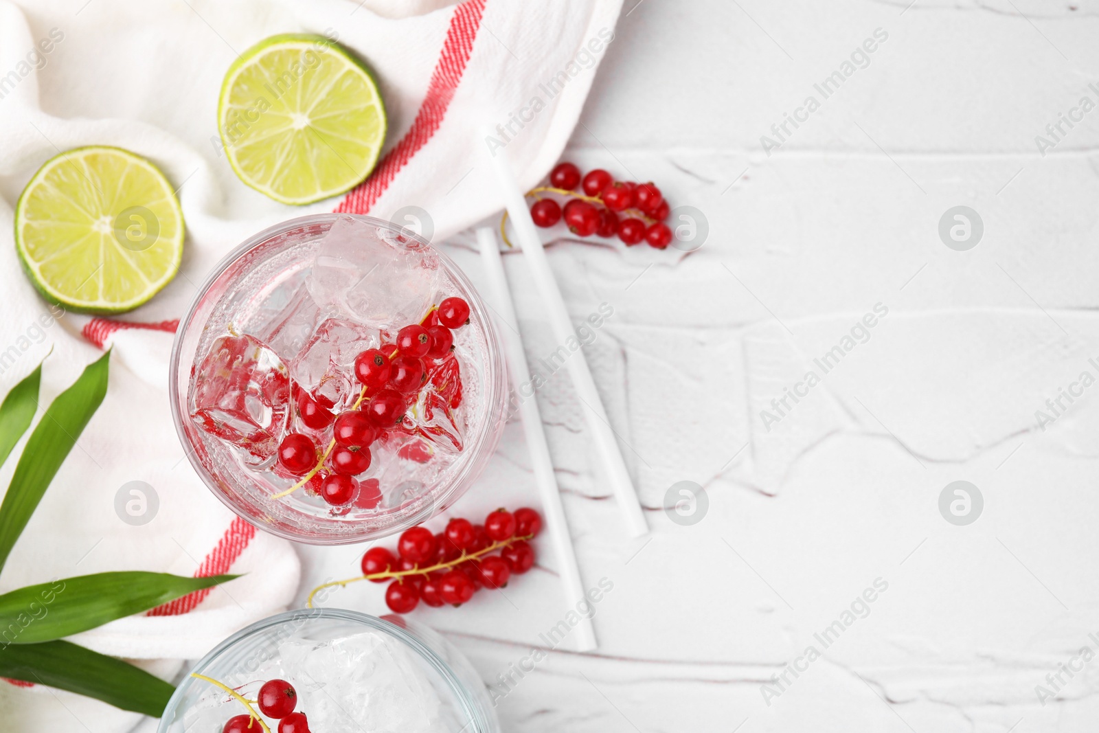 Photo of Refreshing water with red currants in glass on light table, space for text