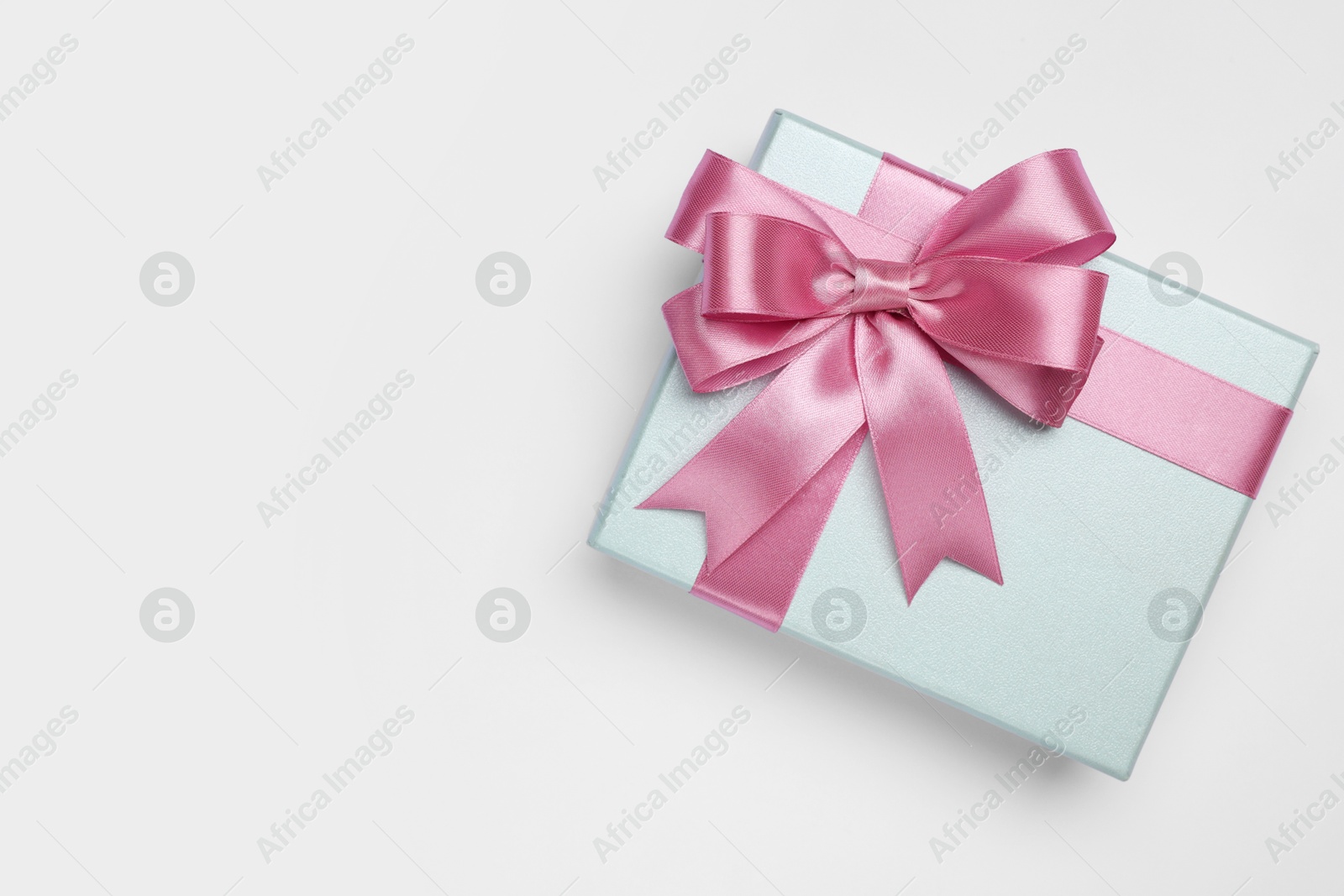 Photo of Gift box with pink bow on light grey background, top view. Space for text