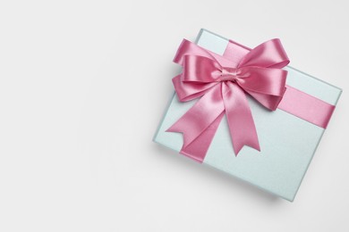 Photo of Gift box with pink bow on light grey background, top view. Space for text