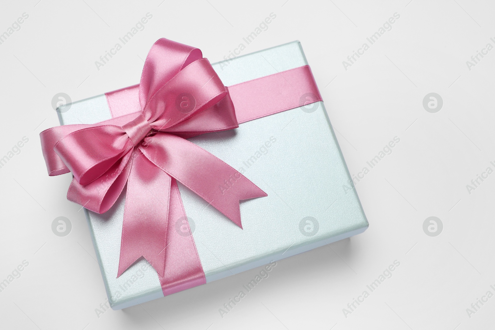 Photo of Gift box with pink bow on light grey background, above view