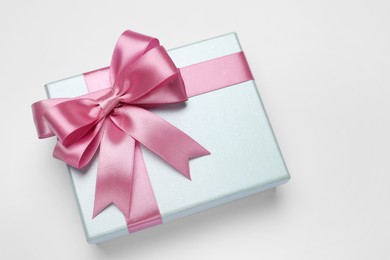 Photo of Gift box with pink bow on light grey background, above view