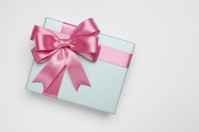 Gift box with pink bow on light grey background, top view. Space for text