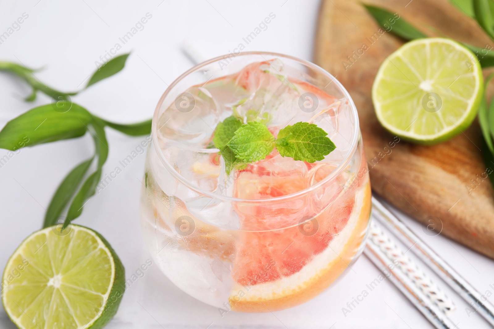 Photo of Refreshing water with grapefruit and mint in glass on white table, closeup