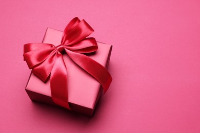 Photo of Gift box with bow on pink background, above view. Space for text