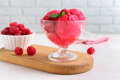 Photo of Delicious raspberry sorbet, mint and fresh berries on white wooden table, closeup