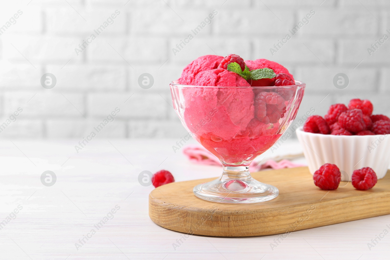 Photo of Delicious raspberry sorbet, mint and fresh berries on white wooden table, space for text