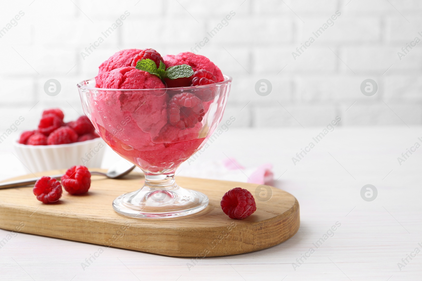 Photo of Delicious raspberry sorbet, mint and fresh berries on white wooden table, space for text