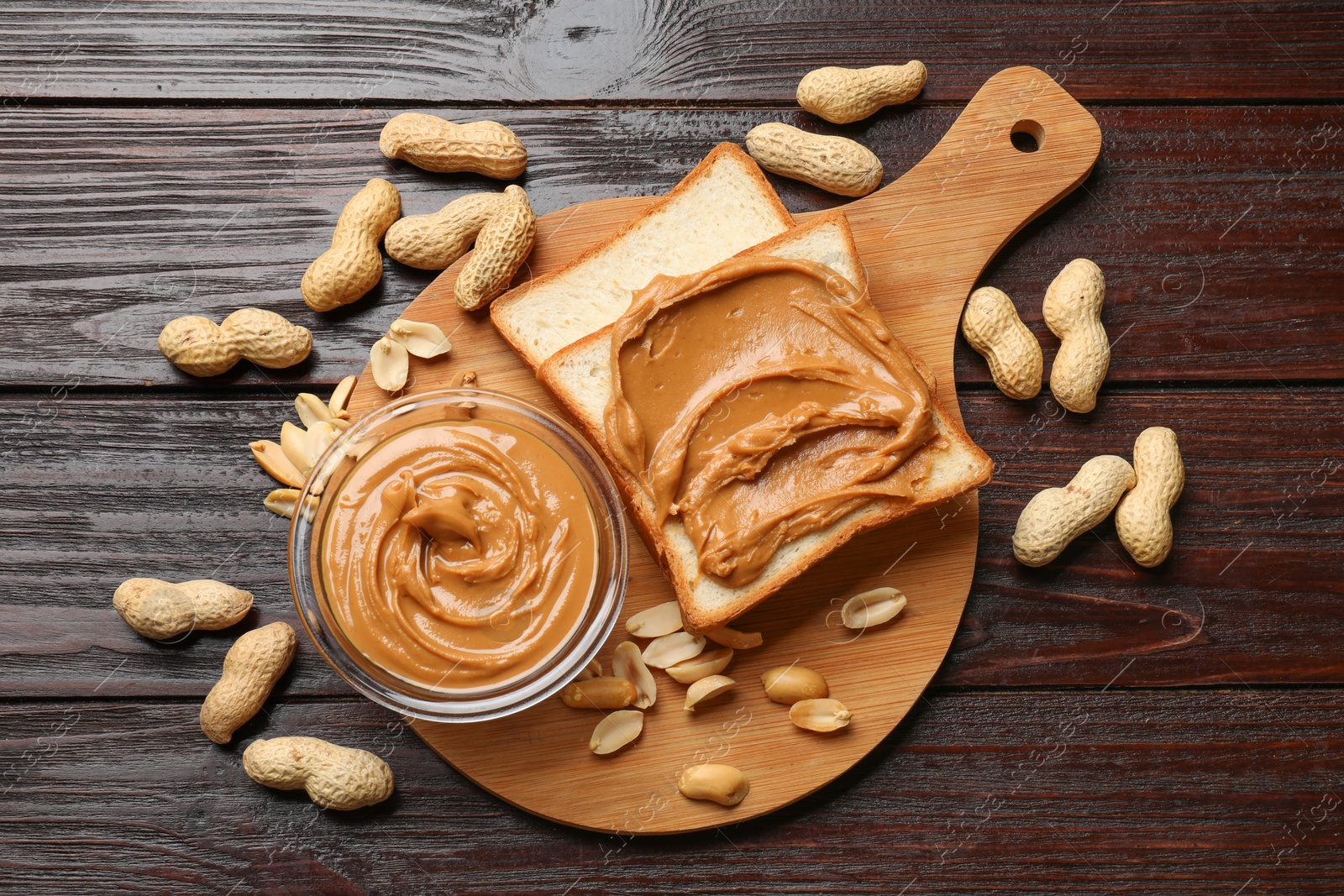 Photo of Delicious sandwich with peanut butter and nuts on wooden table, flat lay