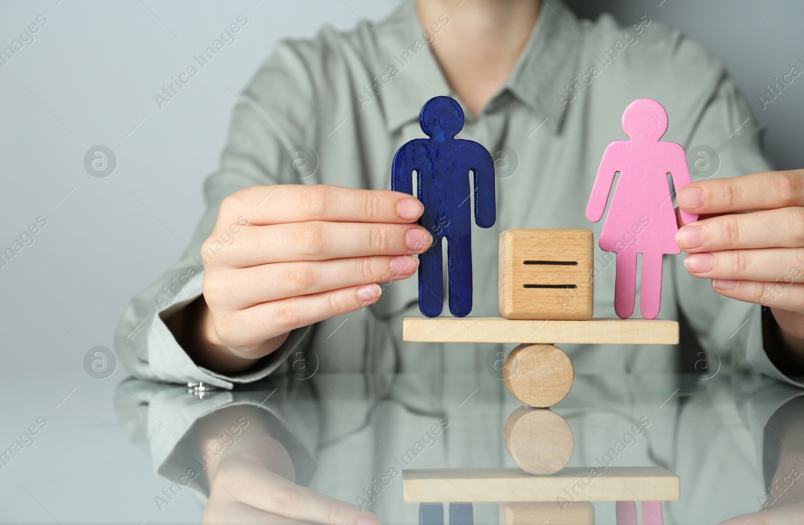 Photo of Gender equality concept. Woman with male and female figures on scales at grey table, closeup