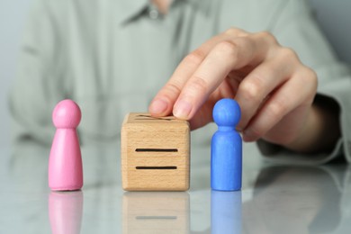 Gender equality concept. Woman with male and female figures at grey table, closeup