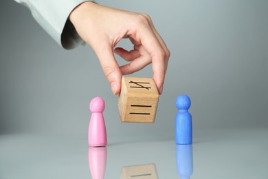 Gender equality concept. Woman with male and female figures at grey table, closeup