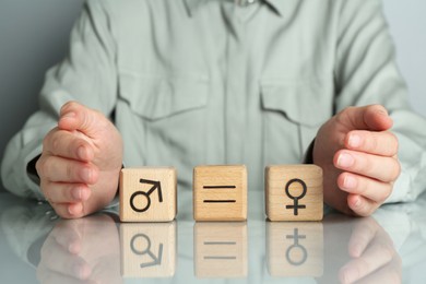 Photo of Gender equality concept. Woman with wooden cubes of male and female symbols at table, closeup