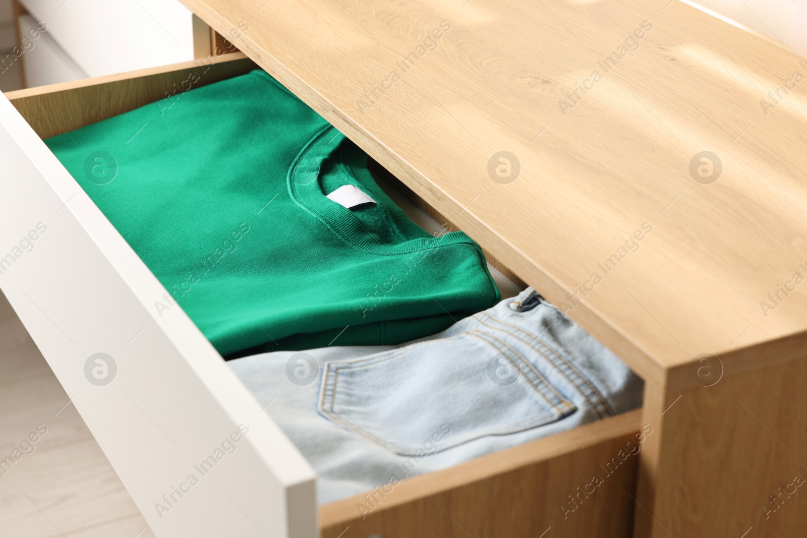 Photo of Chest of drawers with different folded clothes, closeup