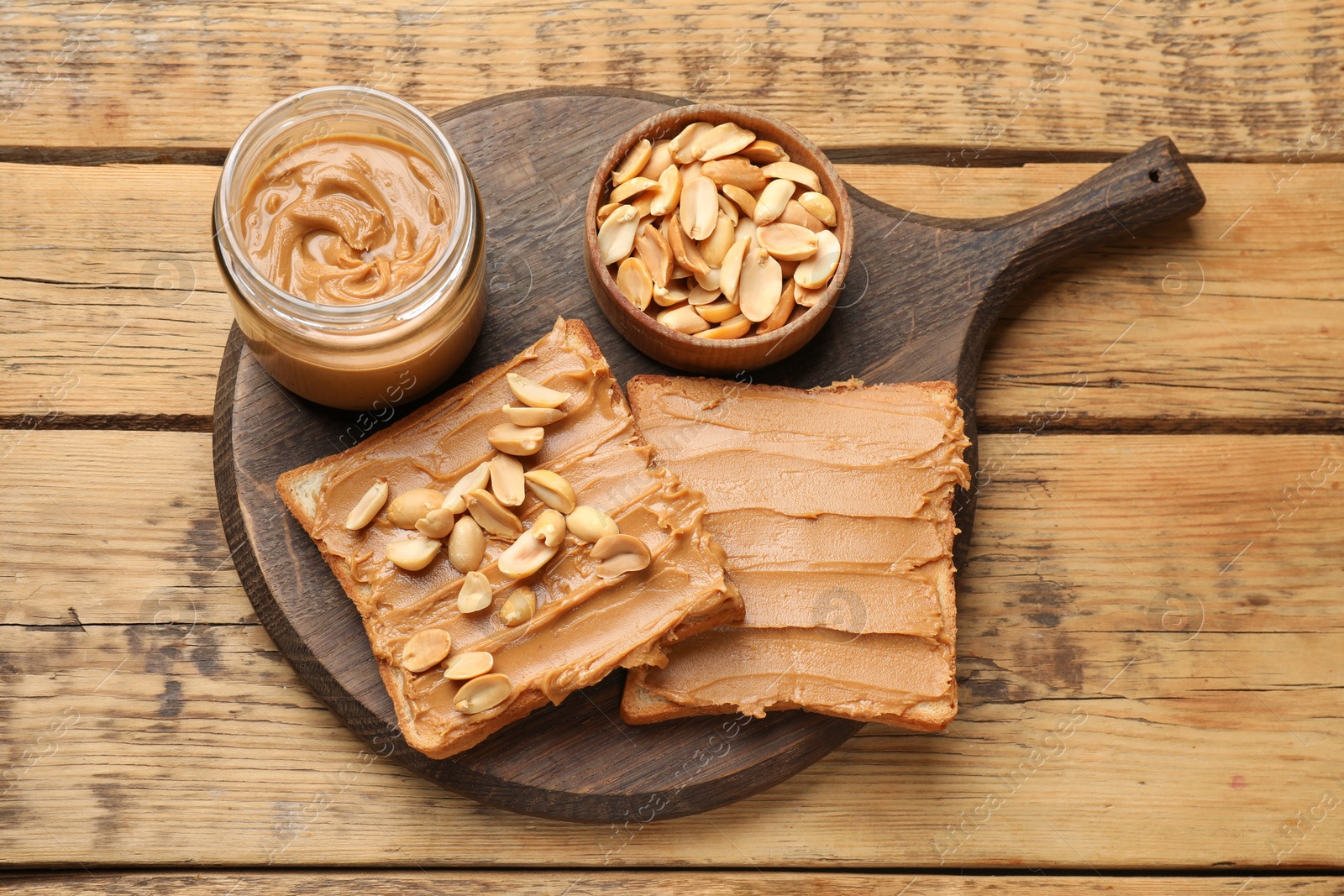 Photo of Delicious sandwiches with peanut butter and fresh nuts on wooden table, top view