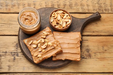 Photo of Delicious sandwiches with peanut butter and fresh nuts on wooden table, top view