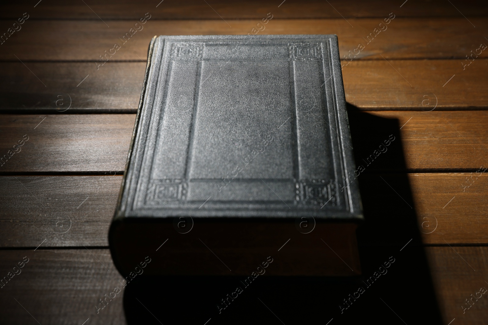 Photo of Closed Bible on wooden table, closeup. Christian faith