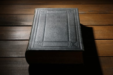 Photo of Closed Bible on wooden table, closeup. Christian faith