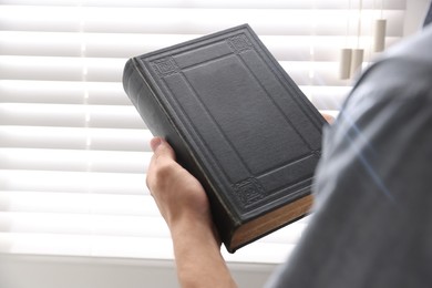 Photo of Man with Bible indoors, closeup. Christian faith