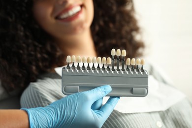 Doctor checking young woman's teeth color in clinic, closeup. Dental veneers