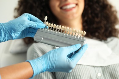 Doctor checking young woman's teeth color in clinic, closeup. Dental veneers