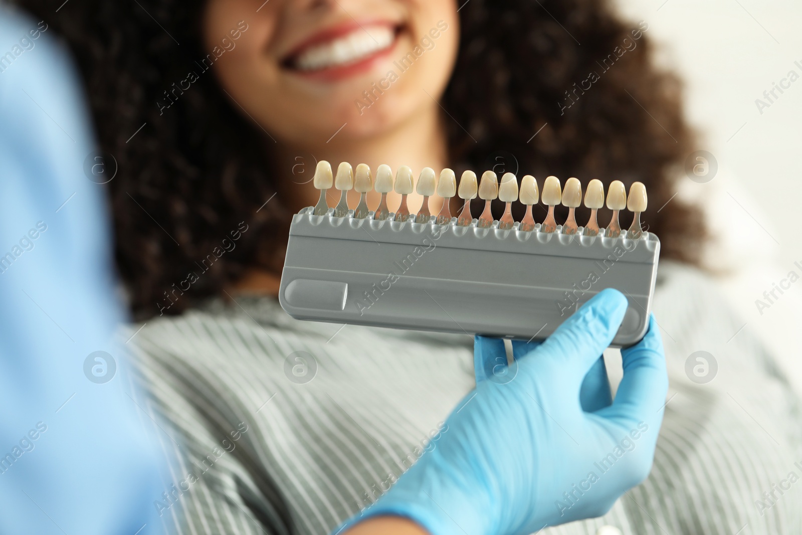 Photo of Doctor checking young woman's teeth color in clinic, closeup. Dental veneers