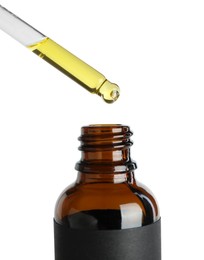 Photo of Dripping tincture from pipette into bottle against white background