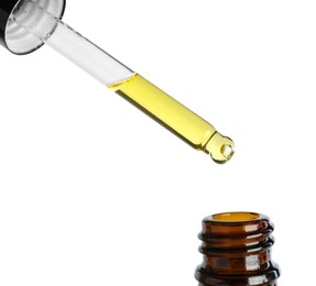 Photo of Dripping tincture from pipette into bottle against white background