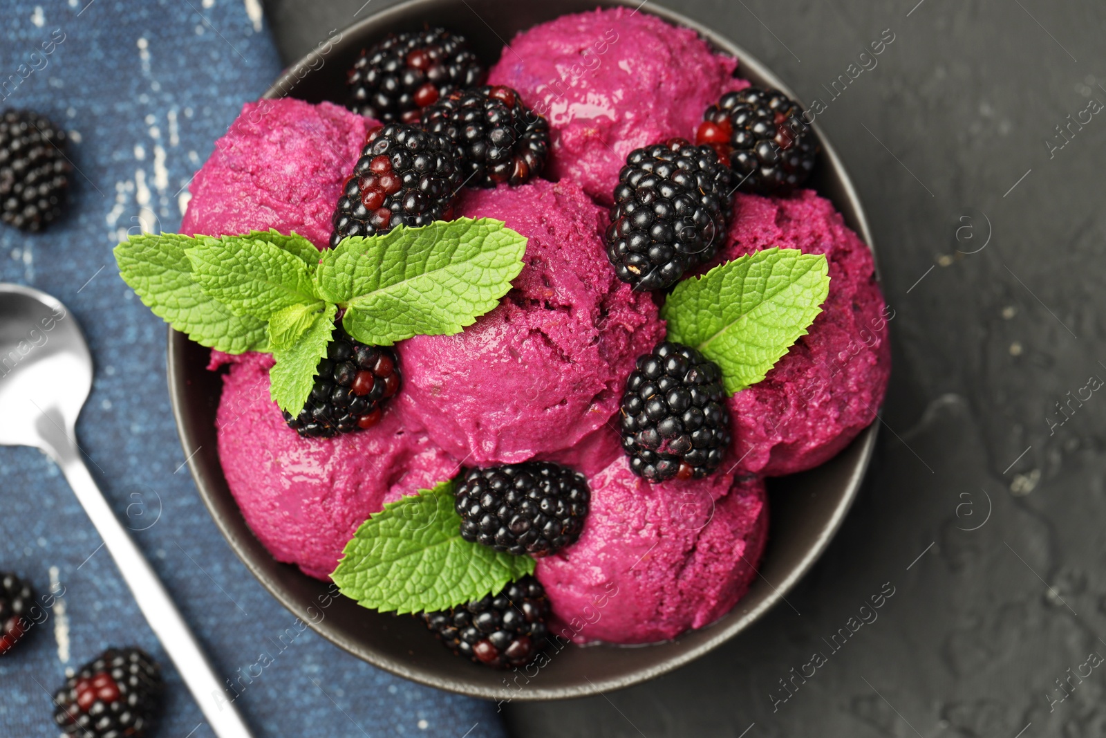 Photo of Delicious blackberry sorbet with fresh berries in bowl and spoon on gray textured table, flat lay